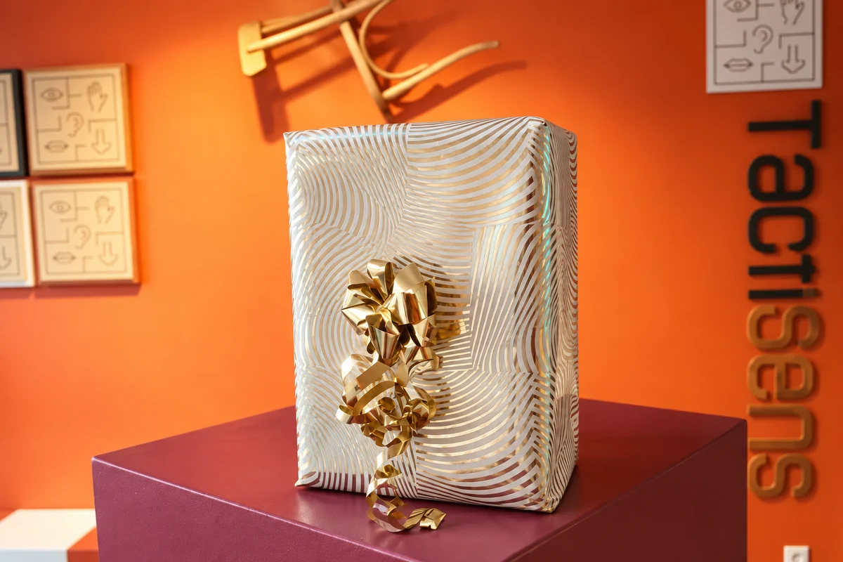 Un cadeau emballé devant le décor orange de Tactisens