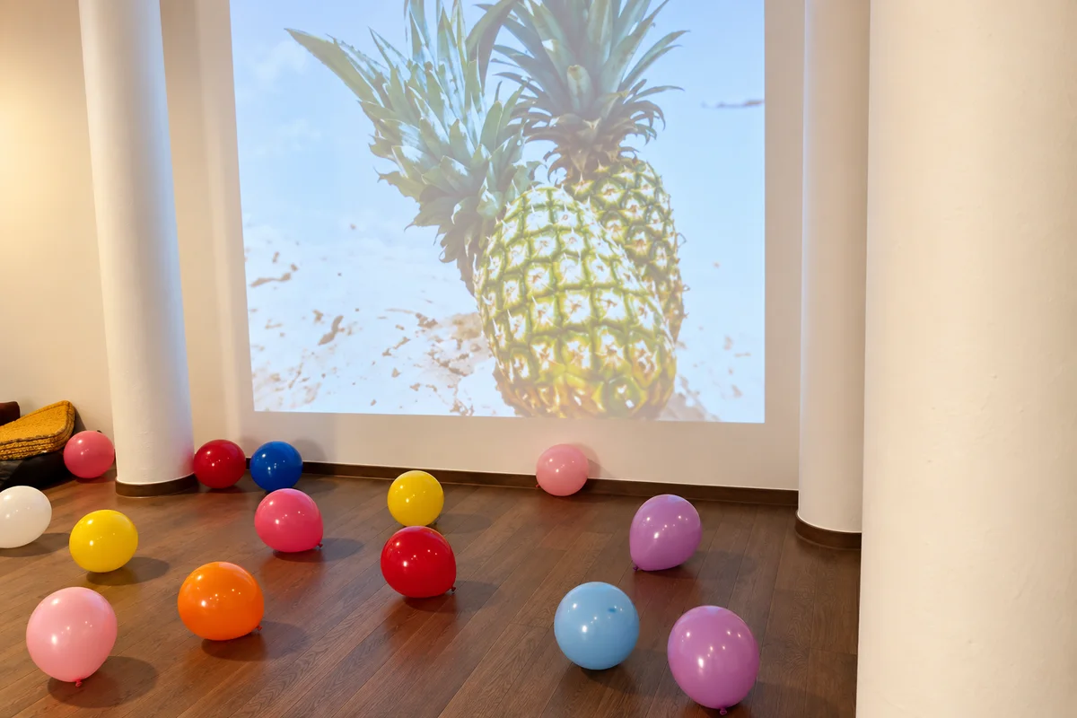 Ballons colorés et projection d’ananas dans la salle anniversaire (photo retouchée)