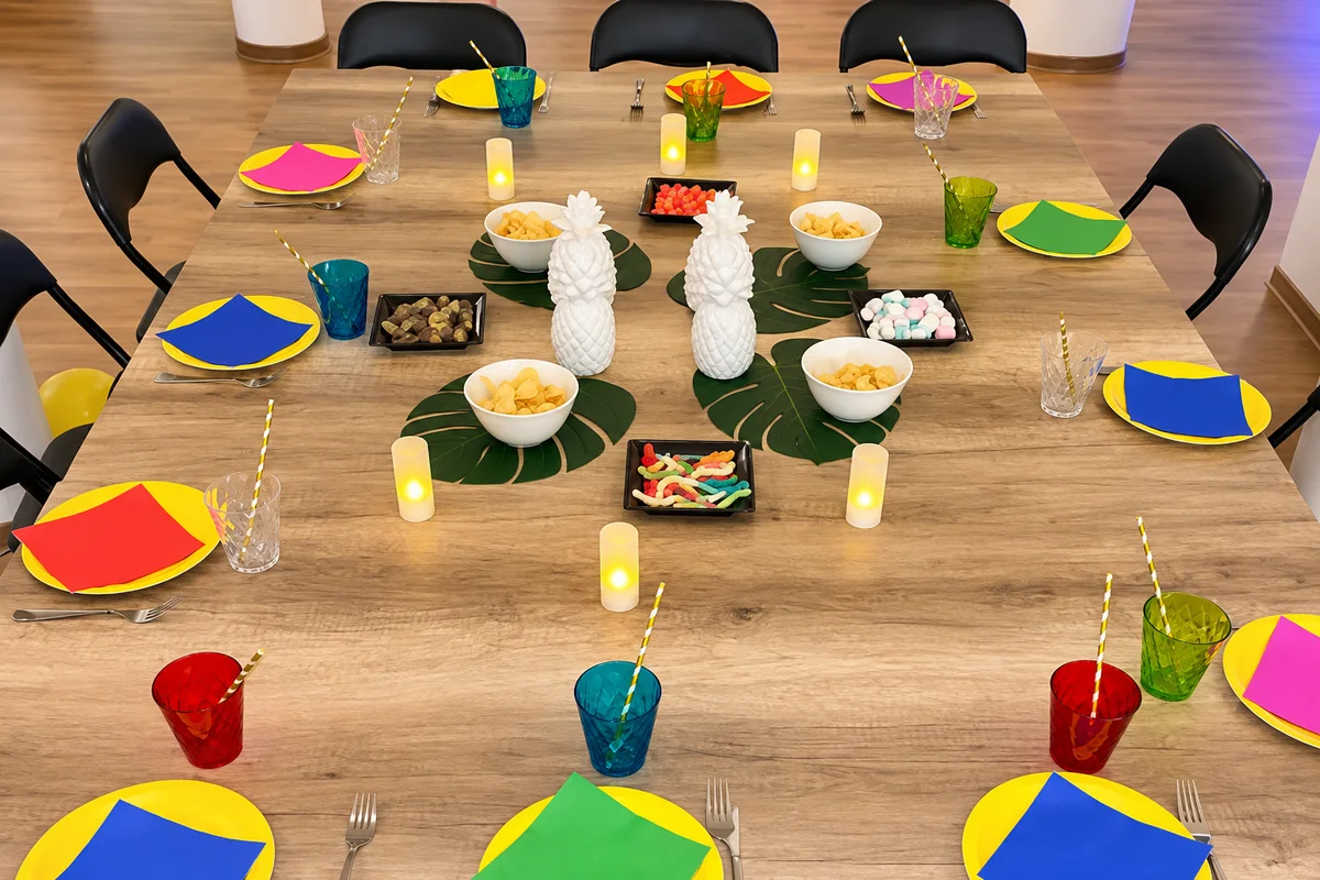 Table du goûter avec assiettes colorées, chips et bonbons (photo retouchée)