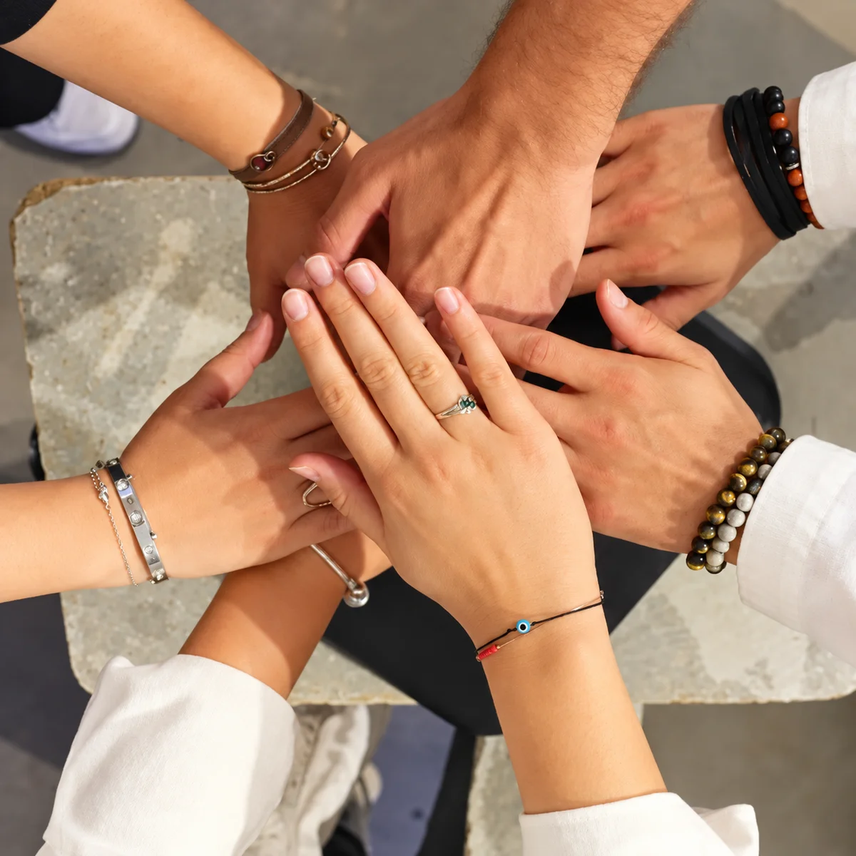 Les mains d’une équipe réunies, vues d’en haut, avec bracelets et bagues