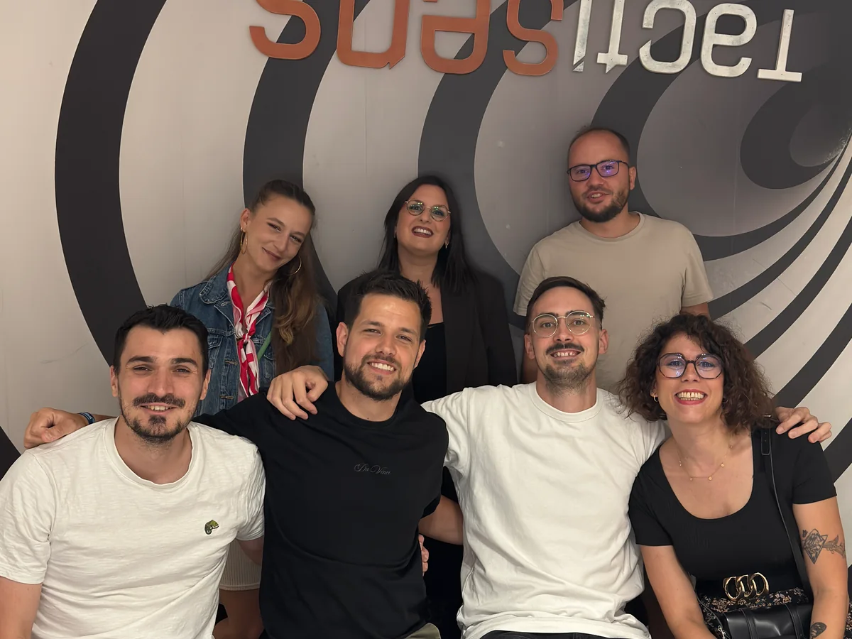 Un groupe pose ensemble devant le mur en spirale de Tactisens