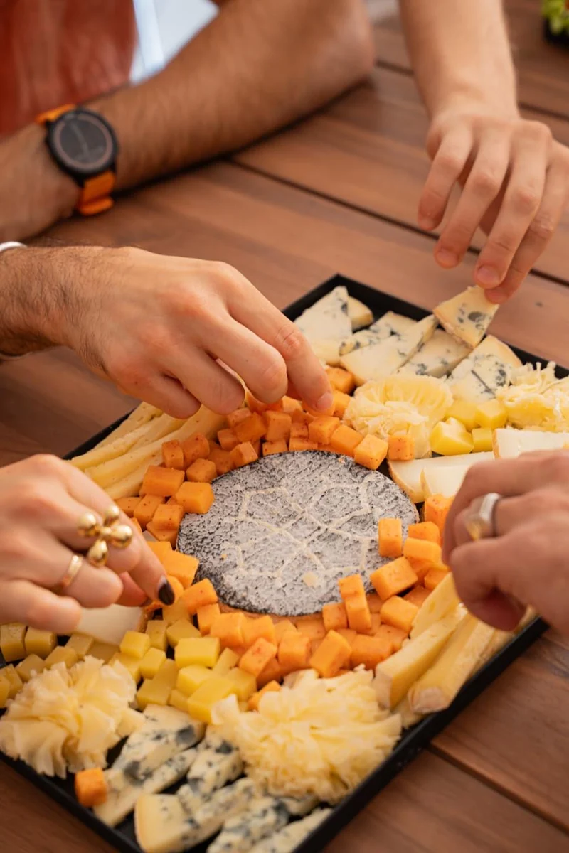 Des convives se servent autour d’un plateau de fromages