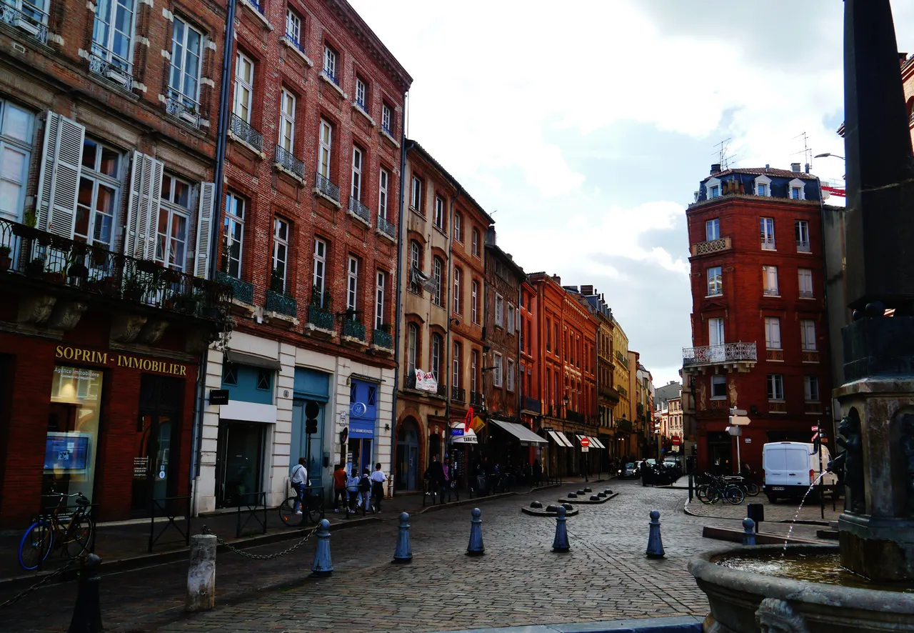 Façades de briques et fontaine sur la place Saint-Étienne à Toulouse.