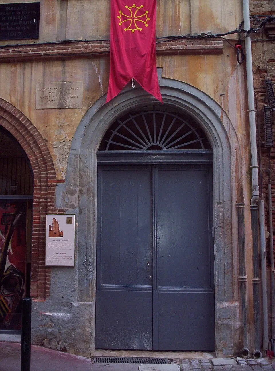 Entrée de l’Ostal d’Occitània dans une façade de briques.